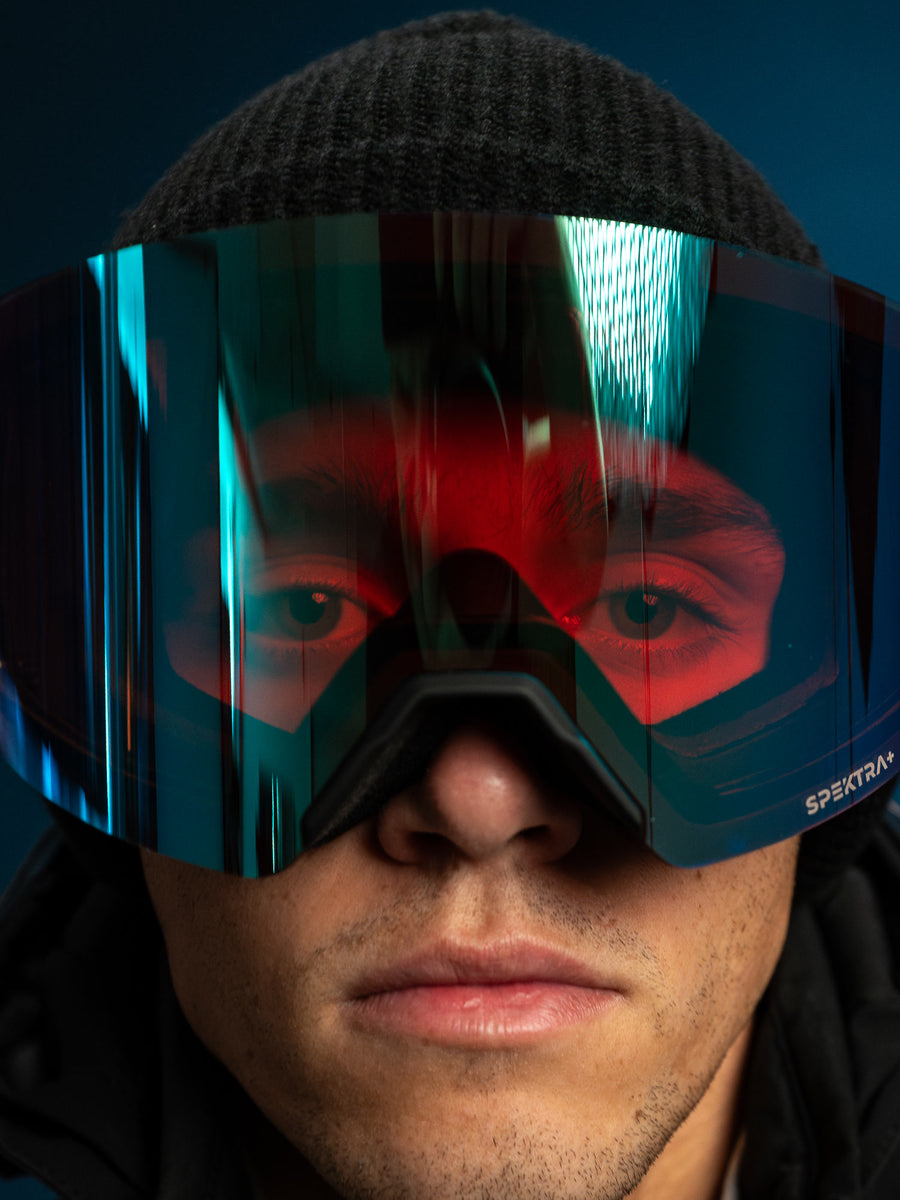 Gros plan d'un skieur dont on voit les yeux à travers la lentille miroir de sa lunette SPEK